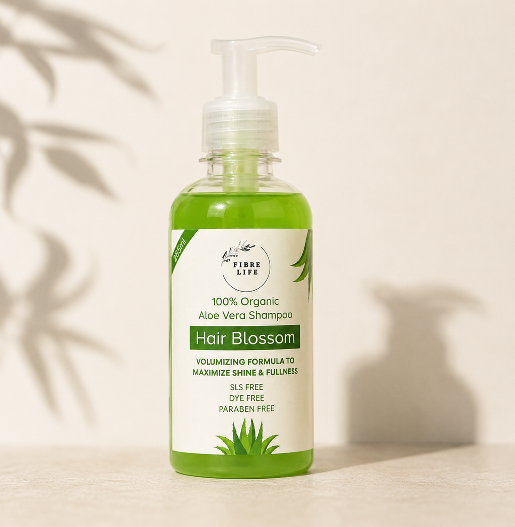 A bottle of Fibre Life Hair Blossom shampoo with a white pump dispenser and a green shampoo liquid inside, set against a warm beige background with soft leaf shadows.